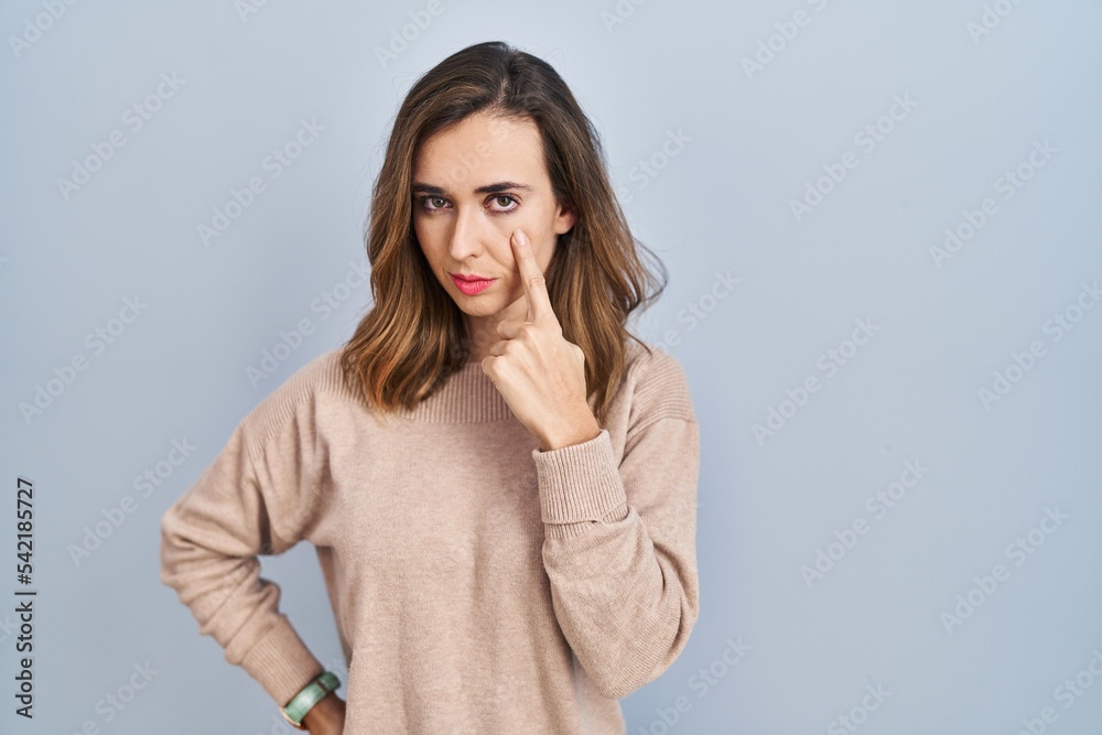 Young woman standing over isolated background pointing to the eye watching you gesture, suspicious expression Young woman standing over isolated background pointing to the eye watching you gesture, suspicious expression