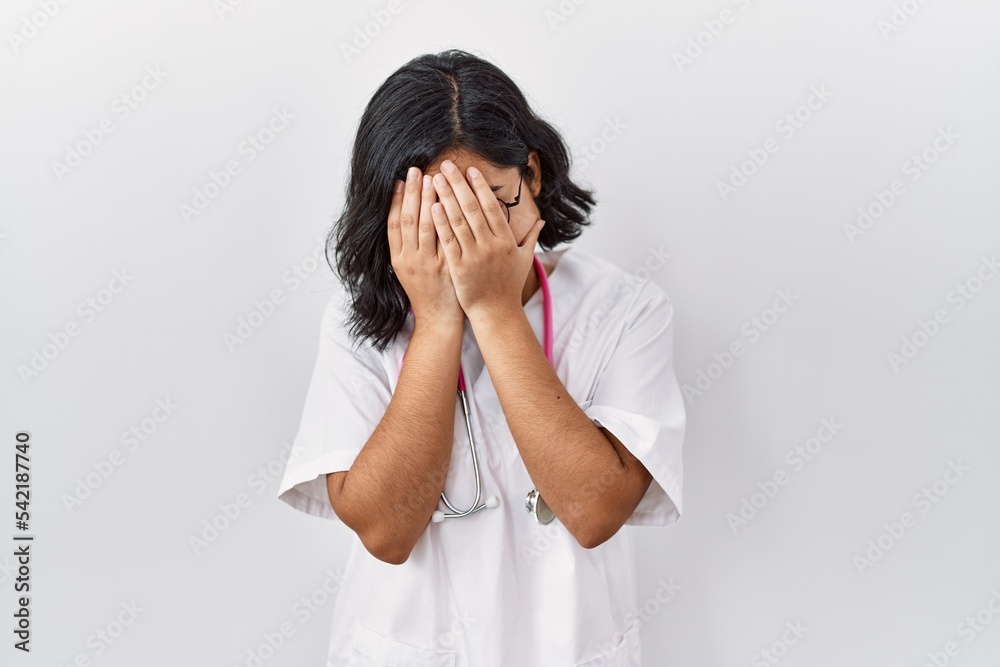 Young hispanic doctor woman wearing stethoscope over isolated background with sad expression covering face with hands while crying. depression concept. Young hispanic doctor woman wearing stethoscope over isolated background with sad expression covering face with hands while crying. depression concept.