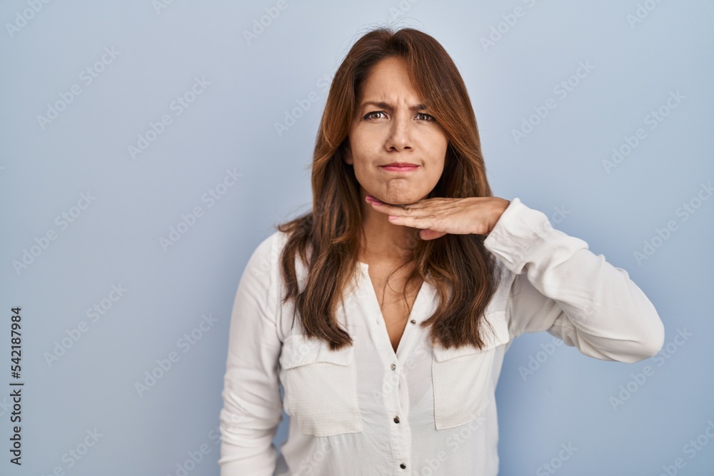 Hispanic woman standing over isolated background cutting throat with hand as knife, threaten aggression with furious violence Hispanic woman standing over isolated background cutting throat with hand as knife, threaten aggression with furious violence