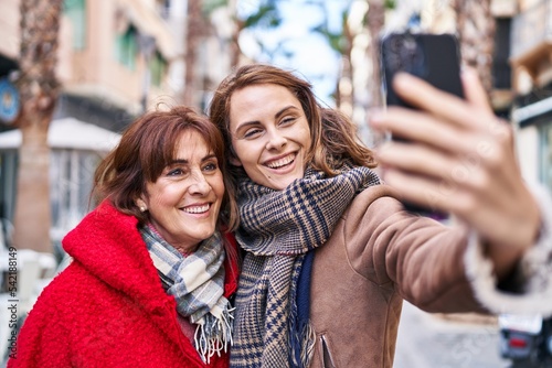 Two women mother and daughter make selfie by smartphone at street