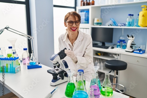 Young caucasian woman wearing scientist uniform using microscope at laboratory
