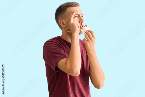 Young man with nosebleed an...