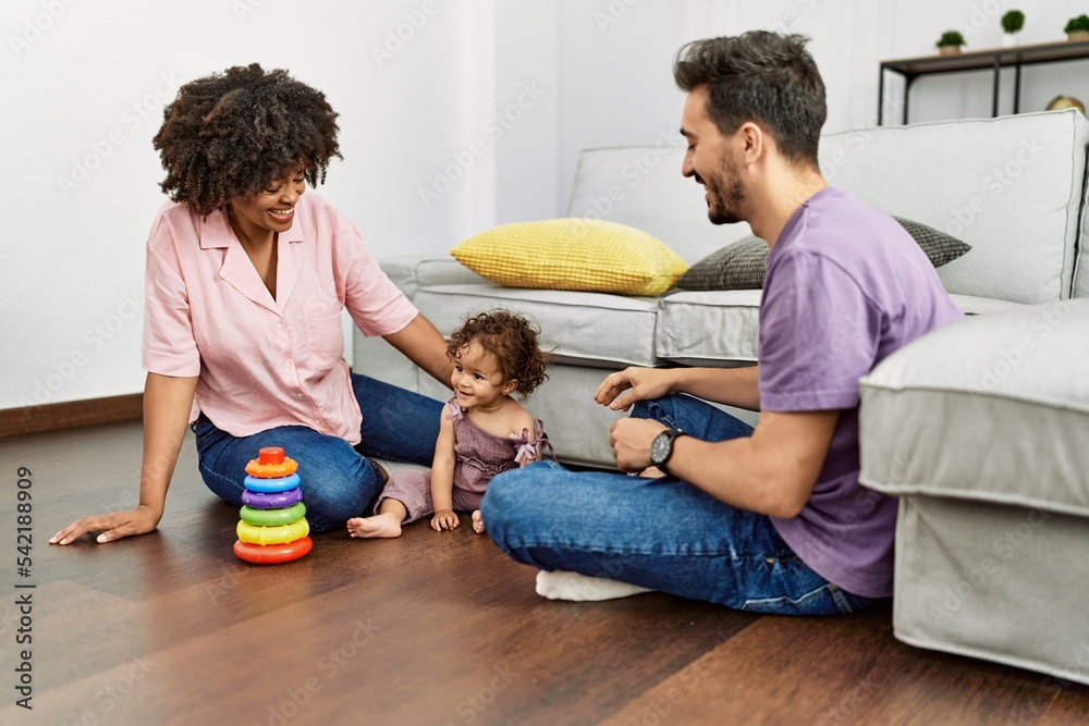 Couple and daughter smiling confident playing with toys sitting on the floor at home