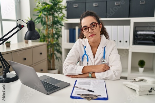 Young hispanic woman wearing doctor uniform and stethoscope looking sleepy and tired  exhausted for fatigue and hangover  lazy eyes in the morning.