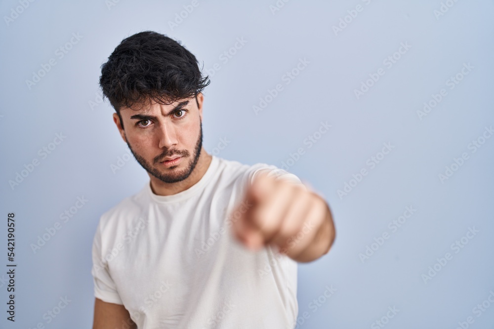 Hispanic man with beard standing over white background pointing displeased and frustrated to the camera, angry and furious with you