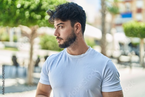 Young hispanic man with relaxed expression standing at street