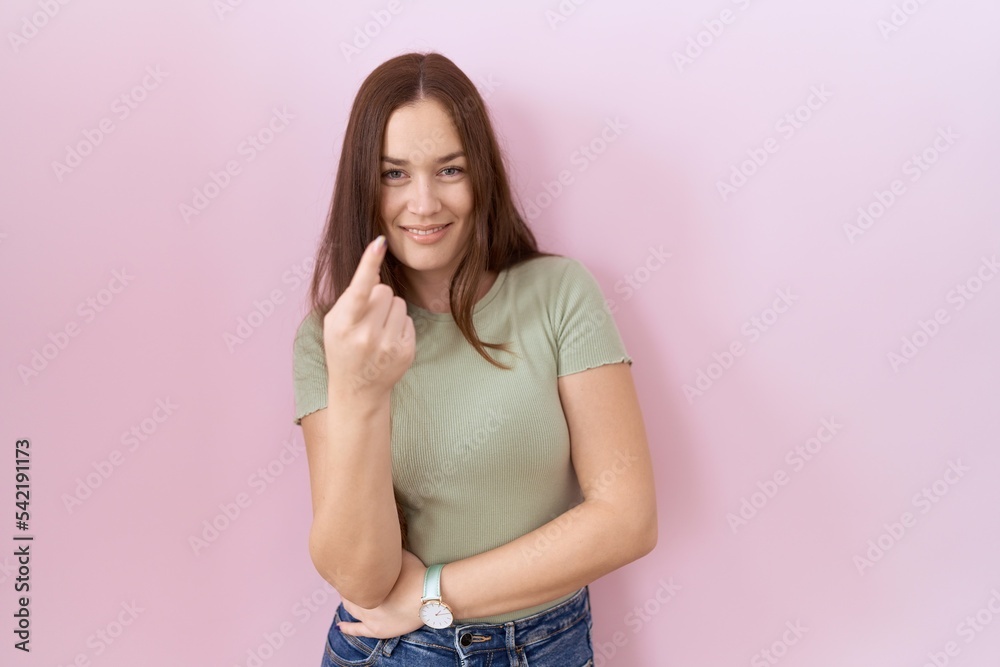 Beautiful brunette woman standing over pink background beckoning come here gesture with hand inviting welcoming happy and smiling Beautiful brunette woman standing over pink background beckoning come here gesture with hand inviting welcoming happy and smiling