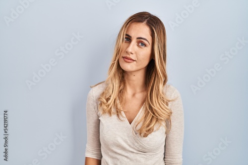Young blonde woman standing over isolated background looking sleepy and tired, exhausted for fatigue and hangover, lazy eyes in the morning.