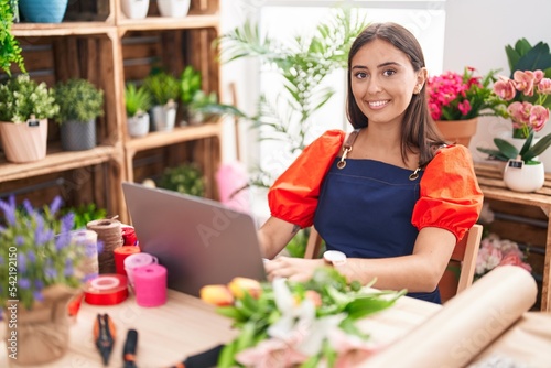 Young beautiful hispanic woman florist smiling confident using laptop at florist