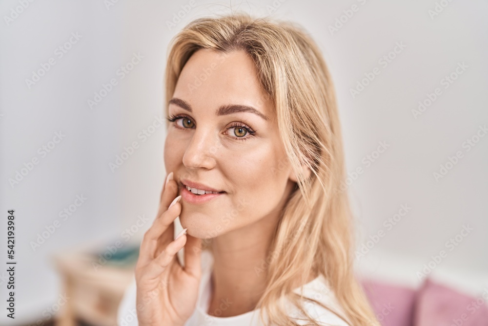 Young blonde woman smiling confident touching face at bedroom Young blonde woman smiling confident touching face at bedroom