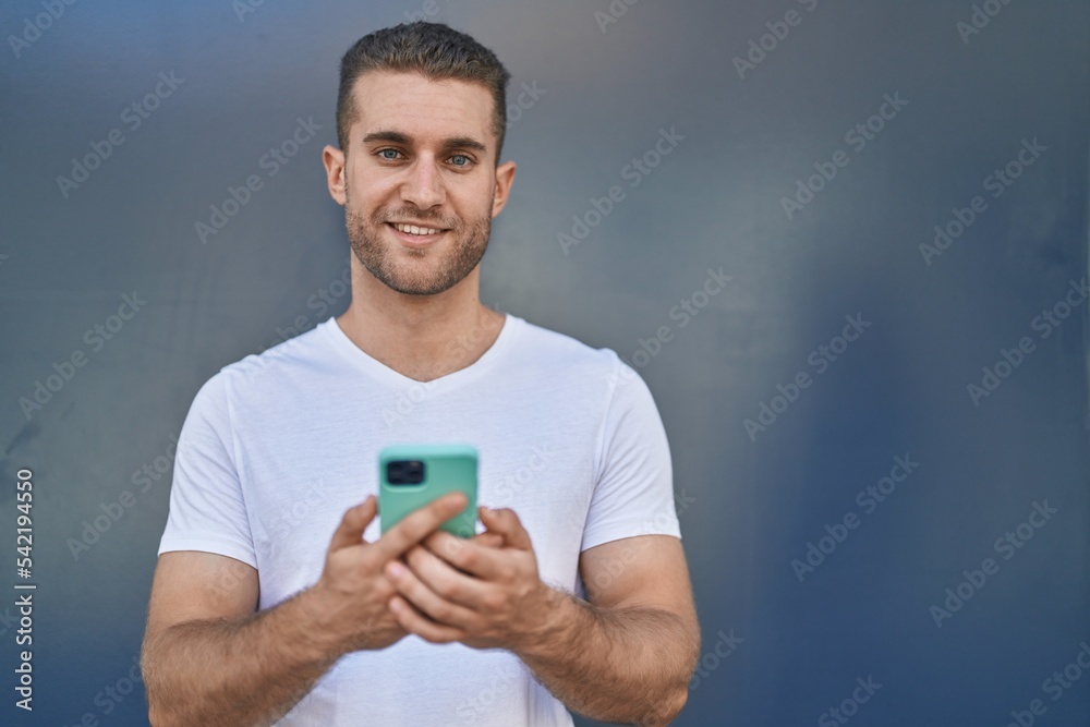 Young caucasian man smiling confident using smartphone over isolated grey background Young caucasian man smiling confident using smartphone over isolated grey background