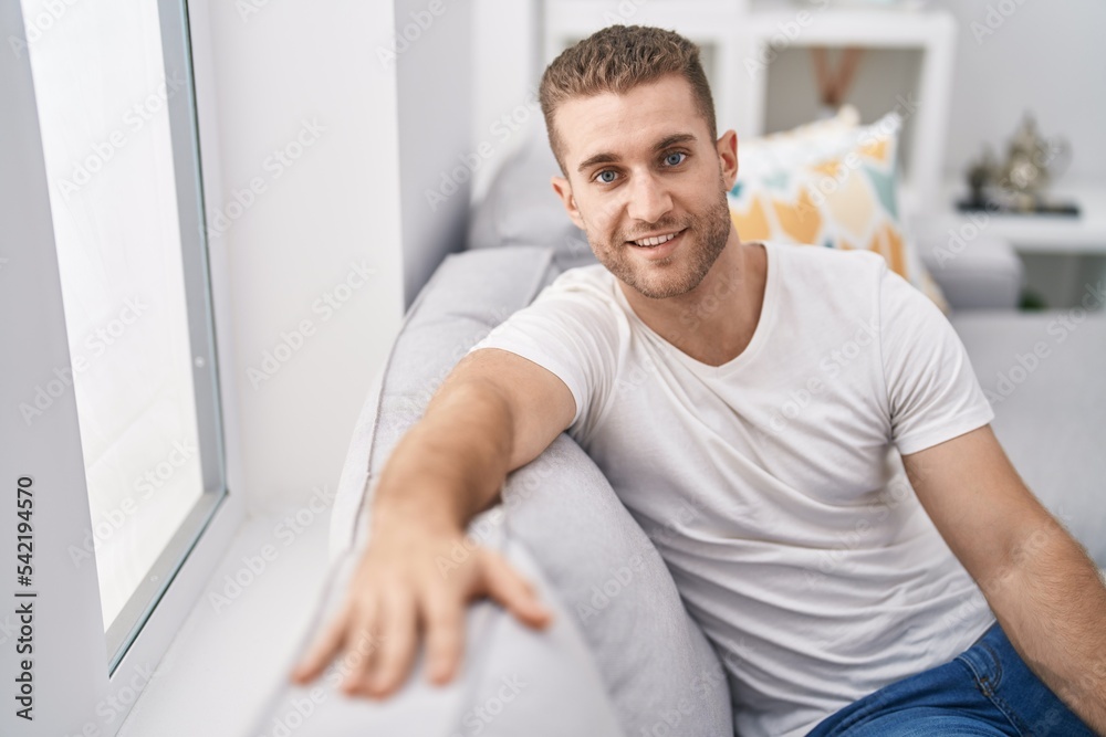Young caucasian man smiling confident sitting on sofa at home Young caucasian man smiling confident sitting on sofa at home