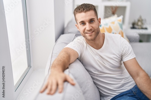 Young caucasian man smiling confident sitting on sofa at home