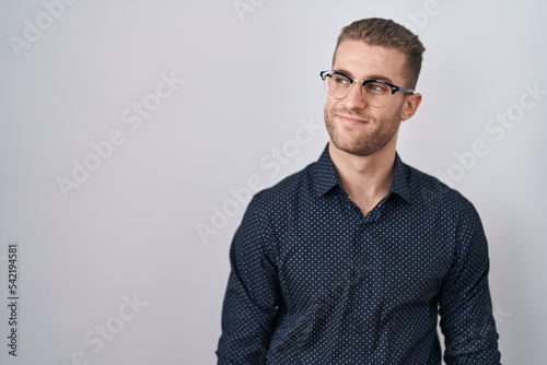 Young caucasian man standing over isolated background smiling looking to the side and staring away thinking. © Krakenimages.com