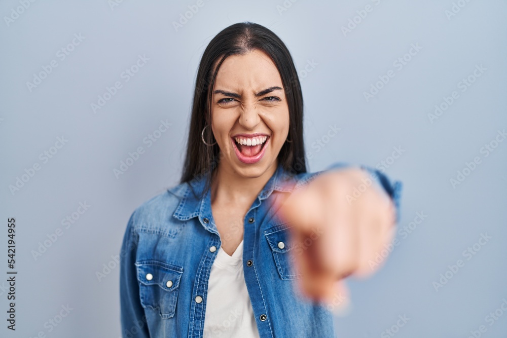 Hispanic woman standing over blue background pointing displeased and frustrated to the camera, angry and furious with you Hispanic woman standing over blue background pointing displeased and frustrated to the camera, angry and furious with you
