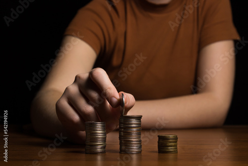 Woman's hand chooses a stack of coins on a black background. interest rate and dividend concept. return on stocks and mutual funds, long term investment for retirement.