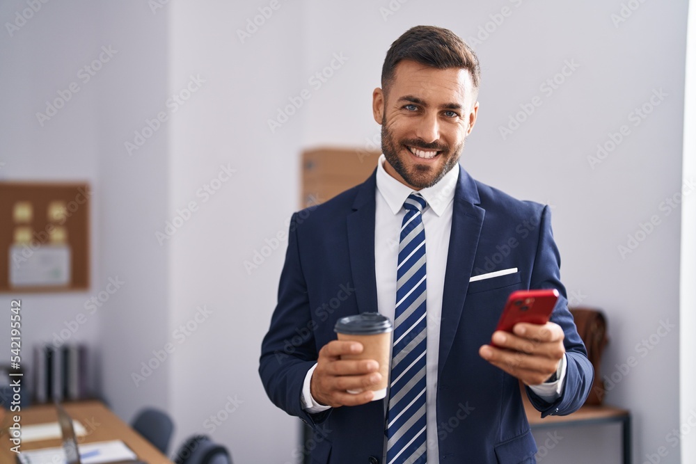 Young hispanic man business worker using smartphone drinking coffee at office