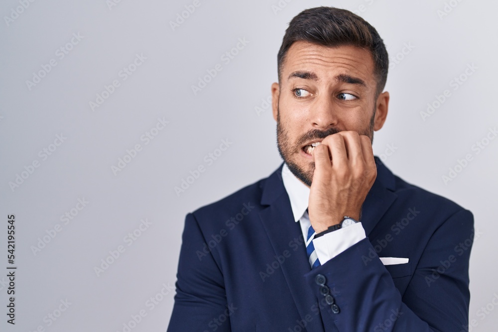 Handsome hispanic man wearing suit and tie looking stressed and nervous with hands on mouth biting nails. anxiety problem. Handsome hispanic man wearing suit and tie looking stressed and nervous with hands on mouth biting nails. anxiety problem.