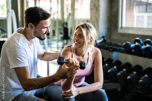 Man and woman working out with dumbbell in fitnes sport gym