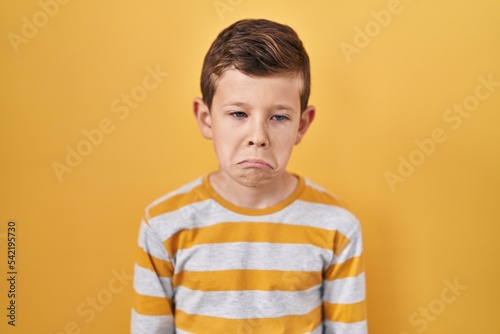 Young caucasian kid standing over yellow background depressed and worry for distress, crying angry and afraid. sad expression.