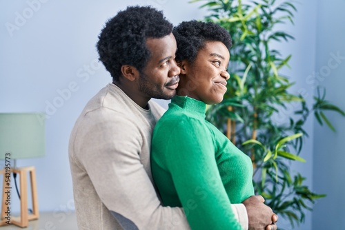 African american man and woman couple hugging each other standing at home