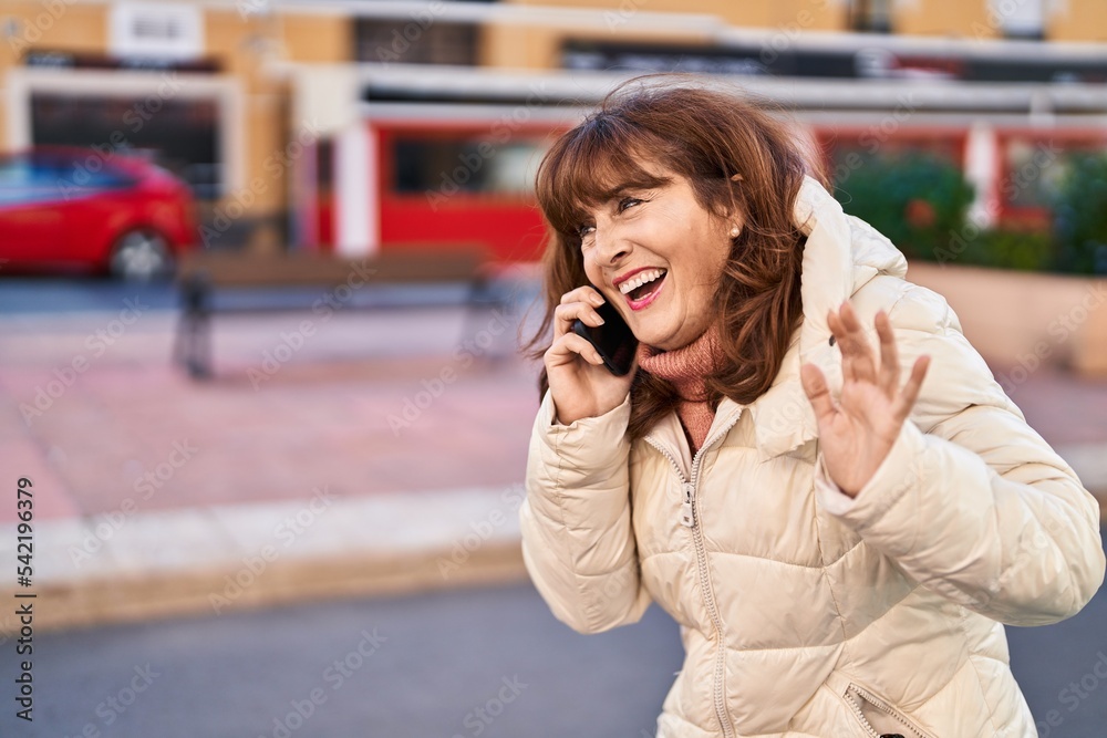 Middle age woman smiling confident talking on the smartphone at street