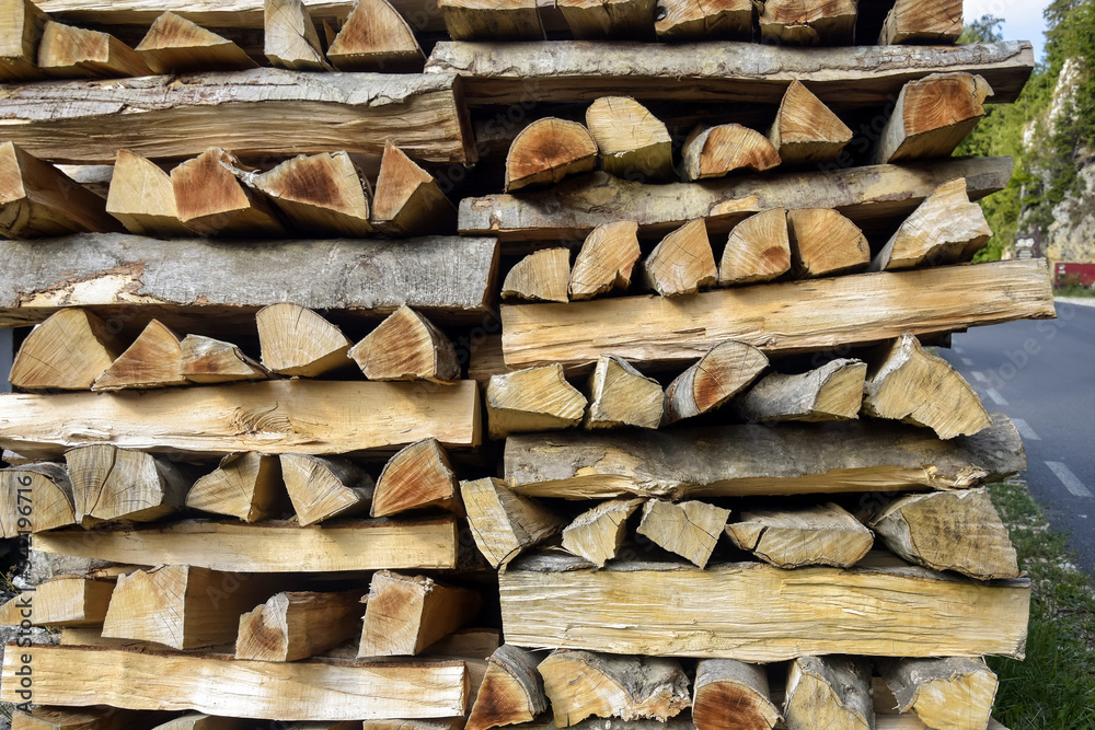 Chopped firewood is stacked in neat piles near highway. Trade in chopped firewood. Preparing firewood for winter. Woodpile. Background. Selective focus. Chopped firewood is stacked in neat piles near highway. Trade in chopped firewood. Preparing firewood for winter. Woodpile. Background. Selective focus.