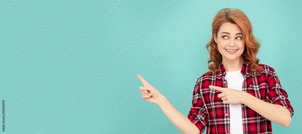 cheerful redhead woman in checkered shirt point finger on blue background. Woman isolated face portrait, banner with mock up copyspace. cheerful redhead woman in checkered shirt point finger on blue background. Woman isolated face portrait, banner with mock up copyspace.