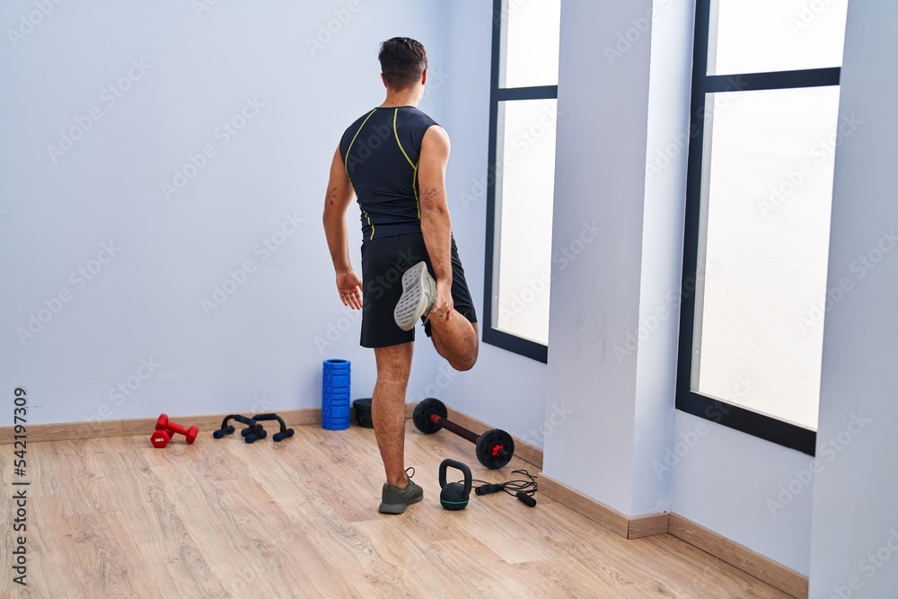 Young hispanic man stretching leg at sport center Young hispanic man stretching leg at sport center