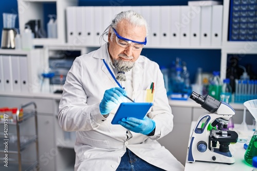 Middle age grey-haired man scientist using touchpad at laboratory