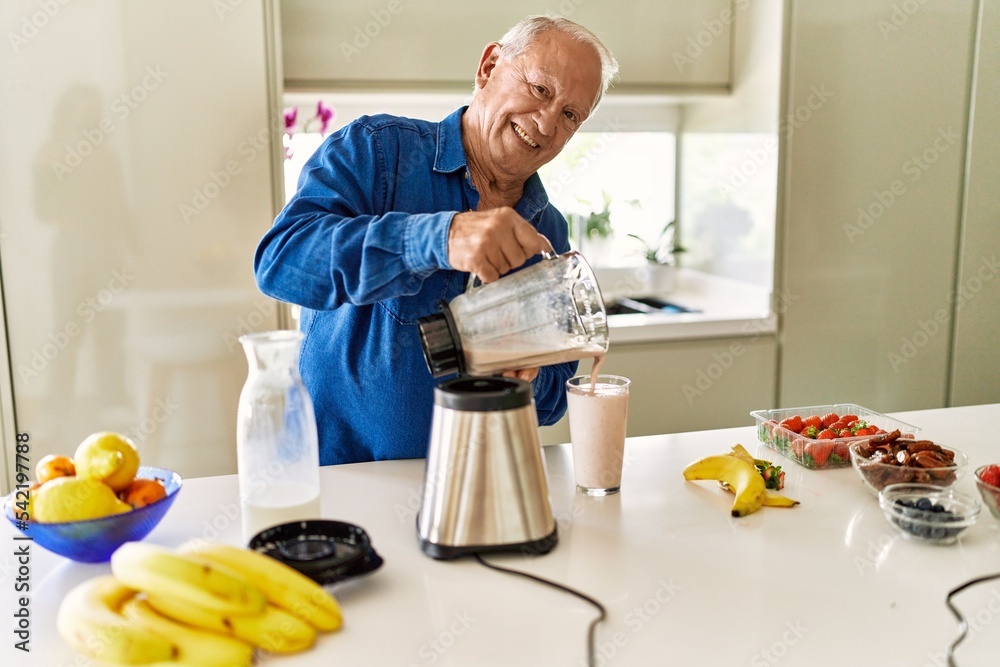 Senior man smiling confident pouring smoothie on glass at kitchen Senior man smiling confident pouring smoothie on glass at kitchen