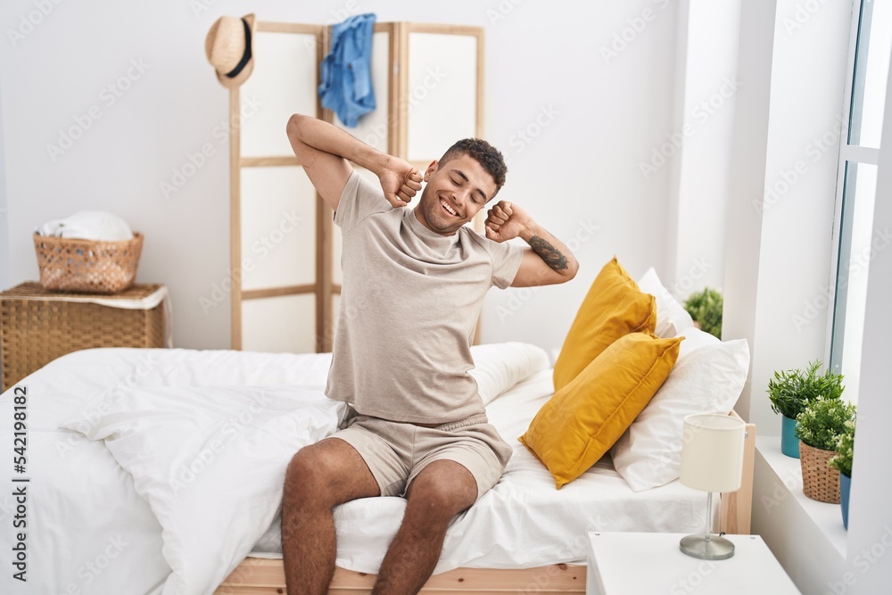 African american man waking up sitting on bed at bedroom - obrazy, fototapety, plakaty 