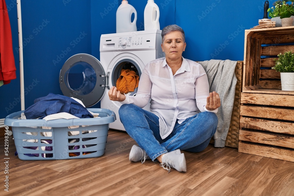 Middle age woman doing yoga exercise waiting for washing machine at laundry room Middle age woman doing yoga exercise waiting for washing machine at laundry room