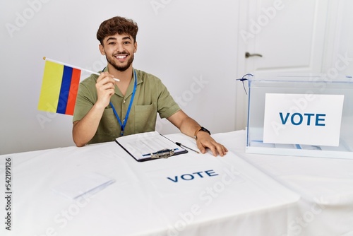 Young arab man smiling confident holding colombia flag working at electoral college photo