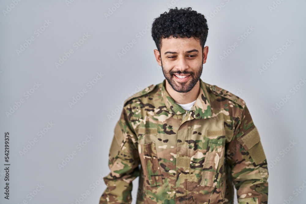 Arab man wearing camouflage army uniform winking looking at the camera with sexy expression, cheerful and happy face.