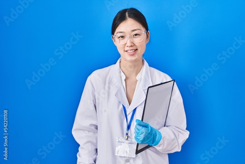 Chinese young woman working at scientist laboratory with a happy and cool smile on face. lucky person.