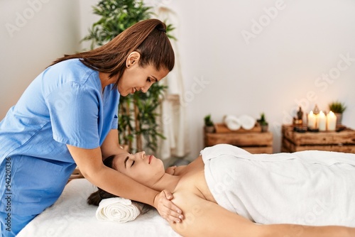 Two women therapist and patient having facial massage session at beauty center