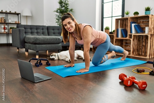 Young woman smiling confident having online abs exercise class at home