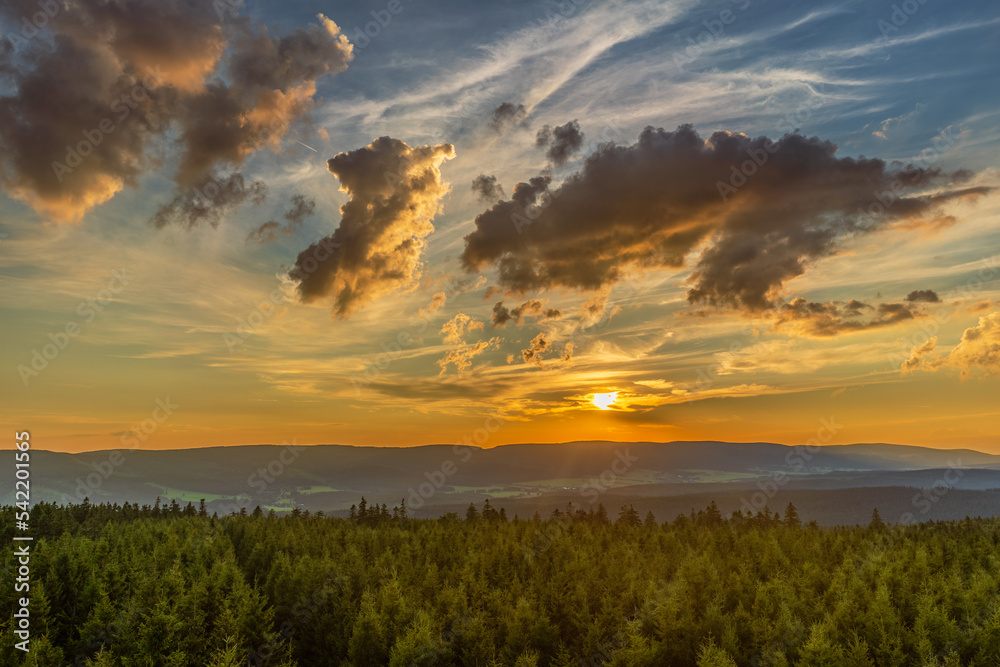 A breathtaking view of a mountain sunset seen from a high vantage point. The warm tones of the setting sun contrast with the cool hues of the rugged mountain landscape, creating a stunning visual disp A breathtaking view of a mountain sunset seen from a high vantage point. The warm tones of the setting sun contrast with the cool hues of the rugged mountain landscape, creating a stunning visual disp