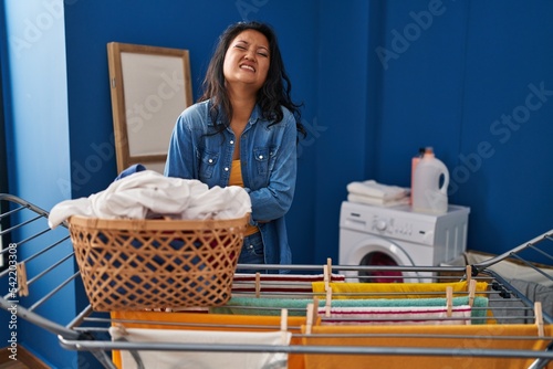 Young asian woman hanging clothes at clothesline with hand on stomach because nausea, painful disease feeling unwell. ache concept.