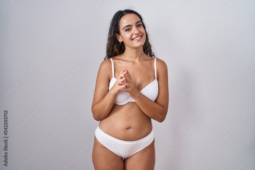 Young hispanic woman wearing white lingerie hands together and fingers crossed smiling relaxed and cheerful. success and optimistic Young hispanic woman wearing white lingerie hands together and fingers crossed smiling relaxed and cheerful. success and optimistic