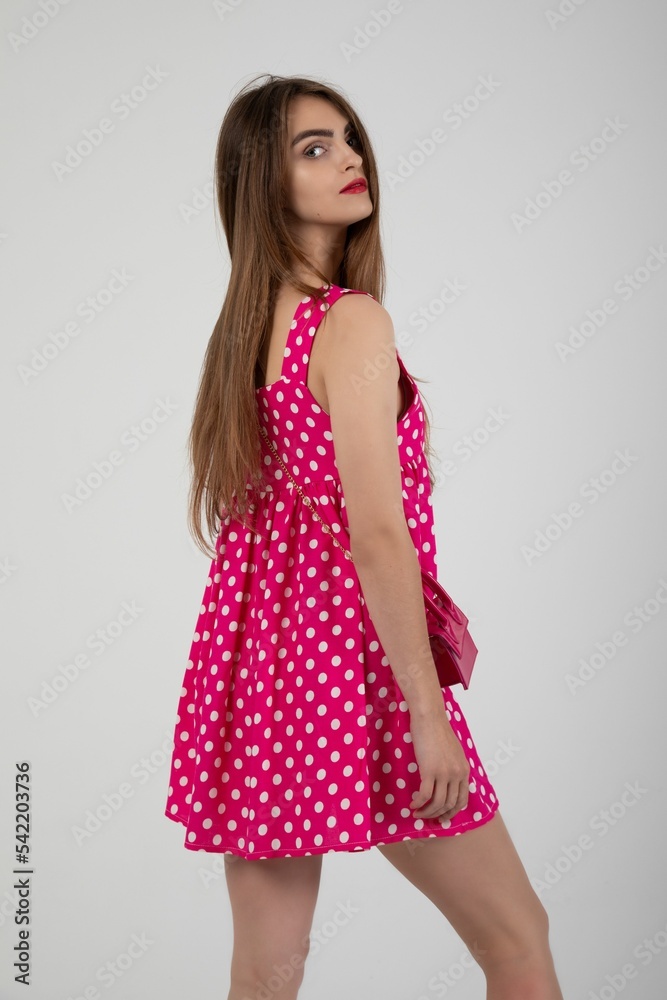 Stunning model posing in a pink polka dot mini dress