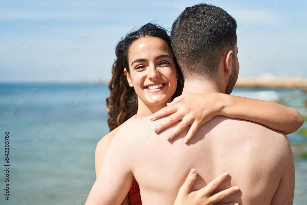 Young hispanic couple tourists wearing swimsuit hugging each other at seaside Young hispanic couple tourists wearing swimsuit hugging each other at seaside