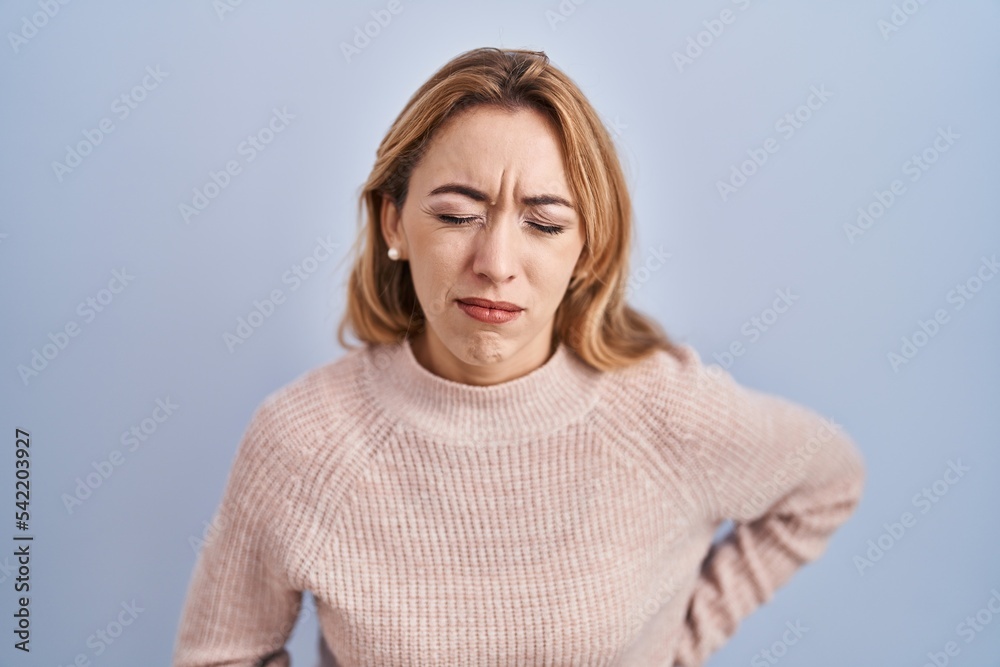 Hispanic woman standing over blue background with hand on stomach because indigestion, painful illness feeling unwell. ache concept. Hispanic woman standing over blue background with hand on stomach because indigestion, painful illness feeling unwell. ache concept.
