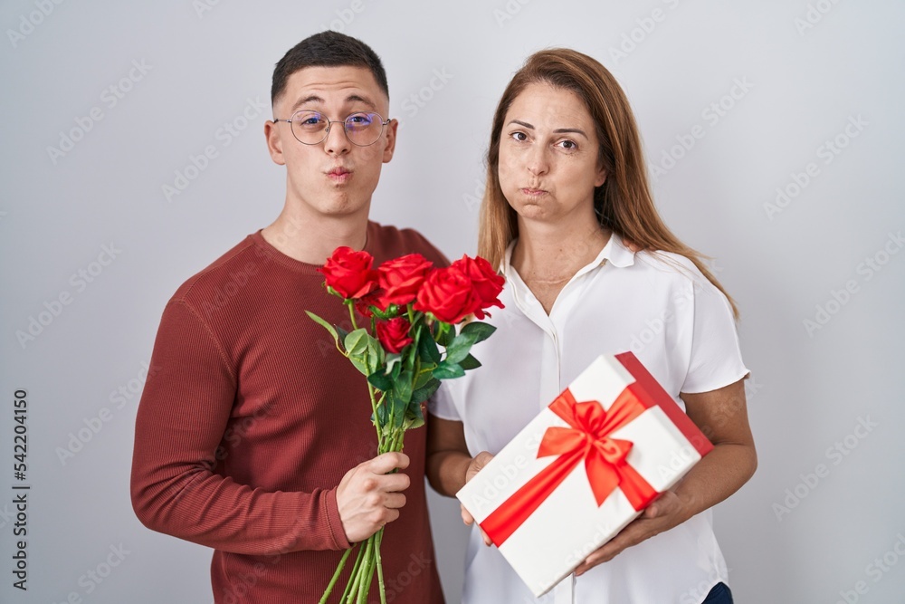 Mother and son holding mothers day gift puffing cheeks with funny face. mouth inflated with air, catching air. Mother and son holding mothers day gift puffing cheeks with funny face. mouth inflated with air, catching air.