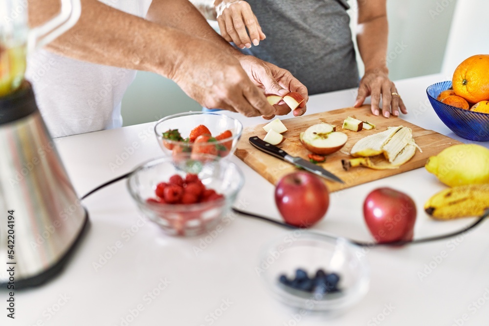 Couple cooking smoothie cutting apple at the kitchen.