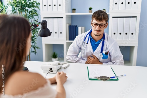 Young doctor with client at medical clinic with hand on stomach because nausea  painful disease feeling unwell. ache concept.