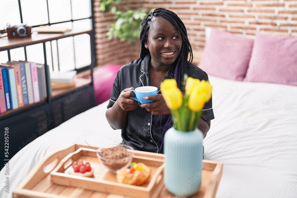 African american woman having gift breakfast sitting on bed at bedroom African american woman having gift breakfast sitting on bed at bedroom