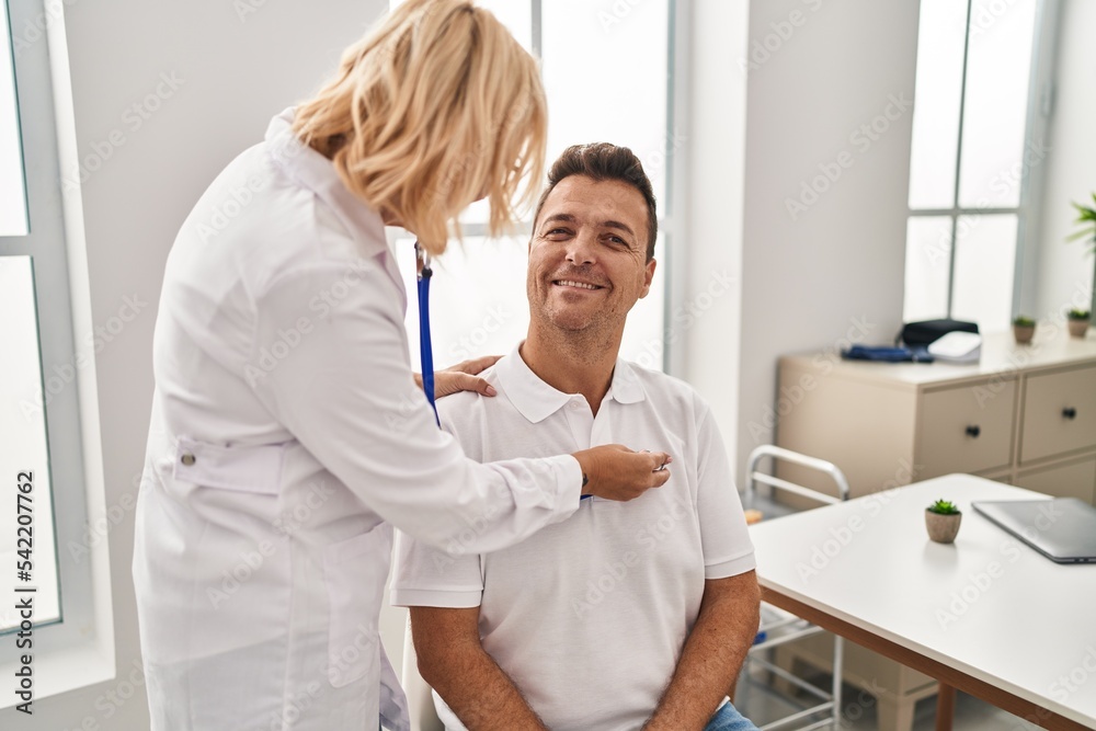 Middle age man and woman doctor and patient auscultating heart having medical consultation at clinic Middle age man and woman doctor and patient auscultating heart having medical consultation at clinic