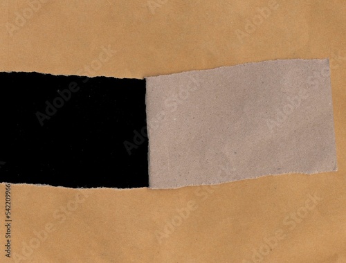 Tear brown paper envelope on black background.